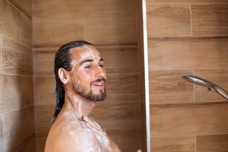 Handsome young man in shower washing his hair with shampoo.の写真素材