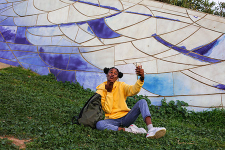 Unidentified indian man sitting on the grass and taking a selfie.の写真素材