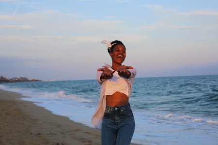 Portrait of a happy young african american woman dancing on the beachの写真素材