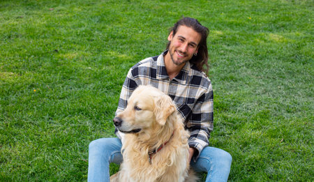 Portrait of a young man sitting with his dog in the parkの写真素材