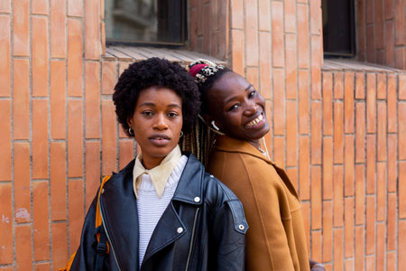 Two african american women walking in the city, wearing stylish clothesの写真素材