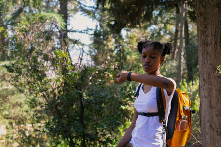Young african american woman hiker with backpack walking in forestの写真素材