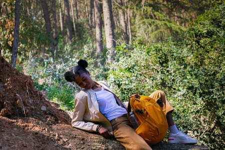 Young woman hiker sitting on a fallen tree in the forest.の写真素材