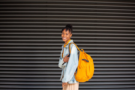 young african american woman with yellow backpack walking in the city