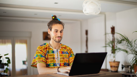 Handsome young man working on his laptop in his home office