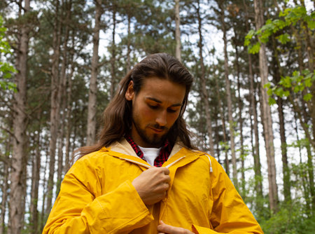 Portrait of a young man in a yellow raincoat in the forestの写真素材