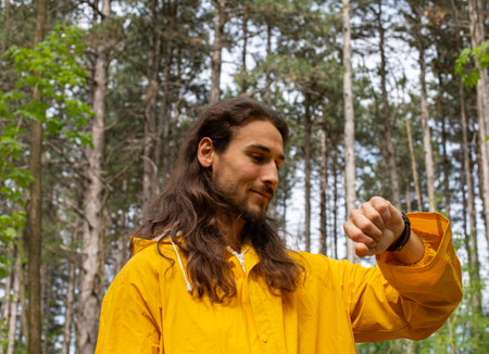Portrait of a young man in a yellow raincoat in the forest.