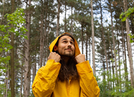 Portrait of a young man in a yellow raincoat in the forestの写真素材