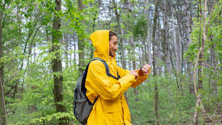 Man in a yellow raincoat with a backpack in the forest.の写真素材