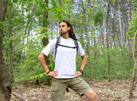 Handsome young man with backpack hiking in the woods. Active lifestyle concept.