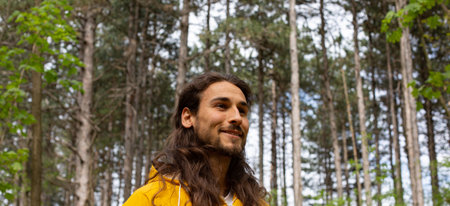 Portrait of a young man in a yellow jacket in the forestの写真素材