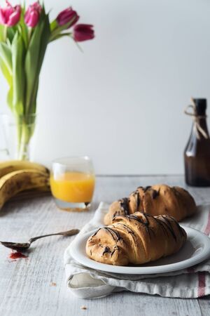 Fresh croissant with chocolate glaze on breakfastの写真素材