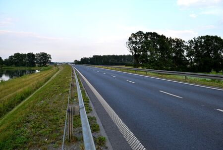 Photo of dark asphalted road and metall barrier 