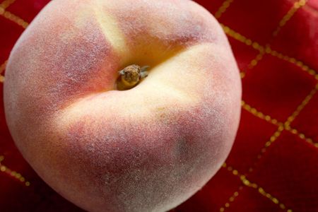 Photo of an organically grown peach on a red tablecloth.の写真素材