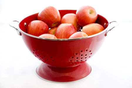 Photo of an organically grown apple in a red colander isolated on white backgroundの写真素材