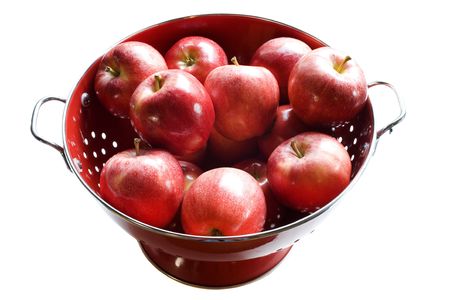 Photo of an organically grown apples in a red colander isolated on white backgroundの写真素材