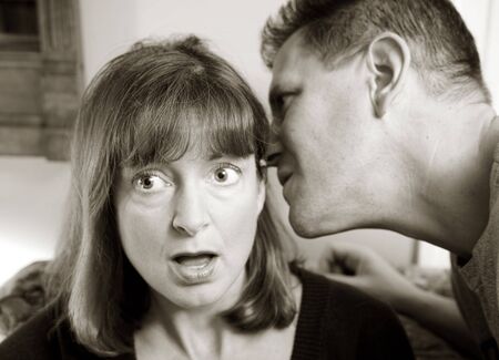 Photo of an attractive man telling a woman a surprising secret.