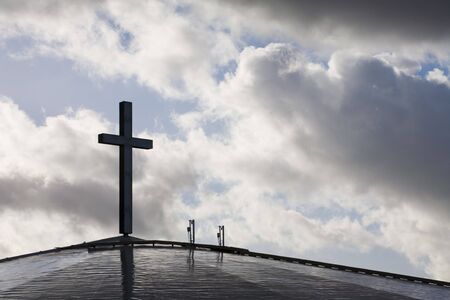 Photo of a cross against blue sky with clouds.の写真素材