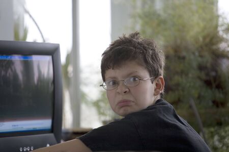 Middle school boy with glasses using a computer. He obviously doesn't like being disturbed.の写真素材