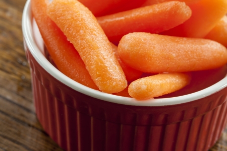 Delicious baby carrots in a red and white bowl.の写真素材