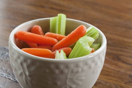 Delicious celery stalks and carrots in a white bowl の写真素材