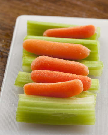 Delicious celery stalks and carrots on white plastiic cutting board の写真素材