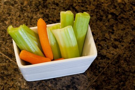 Delicious celery stalks and carrots in a white bowl の写真素材