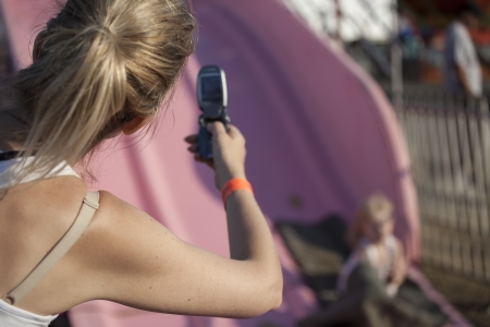 Beautiful, blonde-haired mother takes photo of her daughter with a cheap celll phone.の写真素材