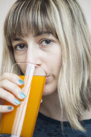 Beautiful young woman drinking a glass of mango juice.の写真素材