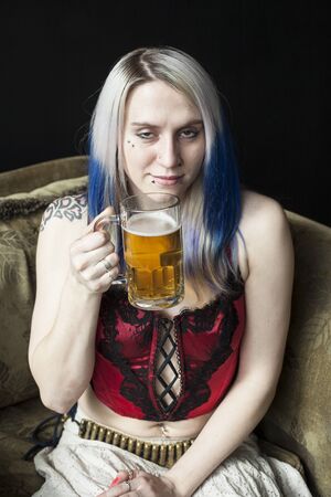 Portrait of a beautiful young woman with blue hair has had  a few too many mugs of beer.の写真素材