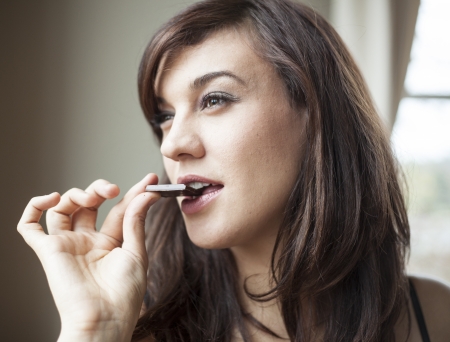 Beautiful young woman eats a piece of dark chocolateの写真素材