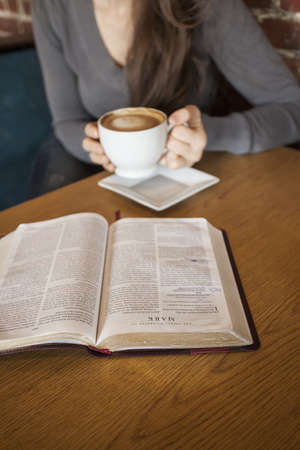 Portrait of a young woman with a white coffee cup reading the book of Mark in the Bibleの写真素材