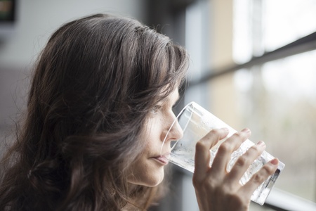 Portrait of a young woman drinking a pint glass of ice water.の写真素材