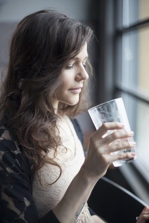 Portrait of a young woman drinking a pint glass of ice water.