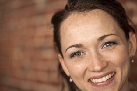 Portrait of a young woman with beautiful brown hair and green eyes sitting in a restaurant with a brick background.の写真素材