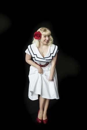 Portrait of a beautiful young woman with blond hair and brown eyes in sailor's dress on a black background.の写真素材