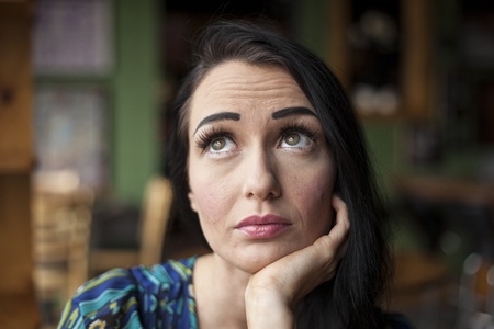 Beautiful young woman with dark brown hair and eyes and a pensive facial expression.の写真素材