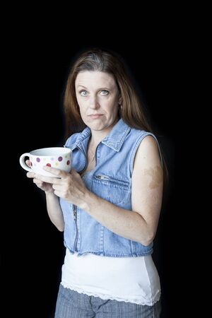 Portrait of a beautiful woman with a strange facial expression and white polka dot coffee cup.の写真素材