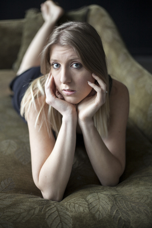 Portrait of a blonde woman on a green couch.の写真素材