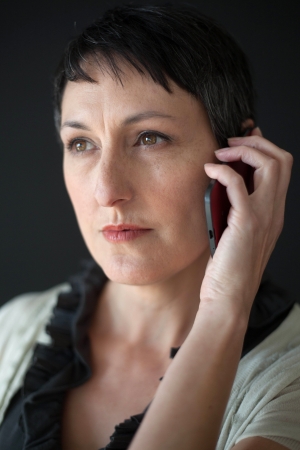 Beautiful older woman with short brown hair and eyes talking on a cell phone.の写真素材