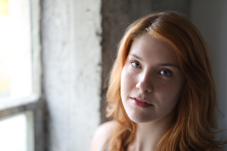 Head short of a very attractive young woman with red hair and stunning blue eyes.の写真素材