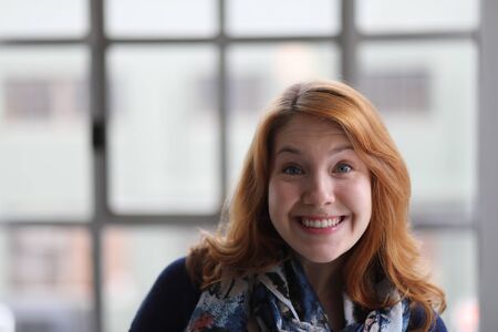 Head shot of a very attractive young woman with red hair and stunning blue eyes. She is wearing a blue scarf and sweater.の写真素材