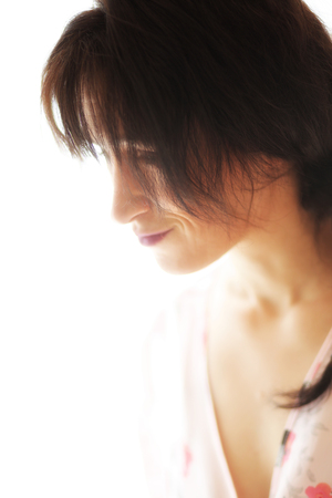 Photo of a very attractive adult woman with brown hair and eyes. She is wearing a pink silk robe.の写真素材