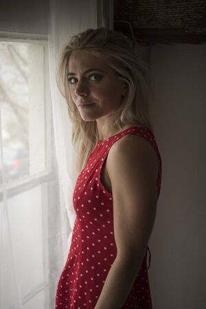 Photo of a very attractive blonde woman with beautiful blue eyes. She is looking straight at the camera and wearing a cute red polka dot dress.の写真素材