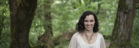 Panoramic photo of a very attractive 40-year-old woman with brown hair and eyes. She is standing in a wooded are and wearing a white top.の写真素材