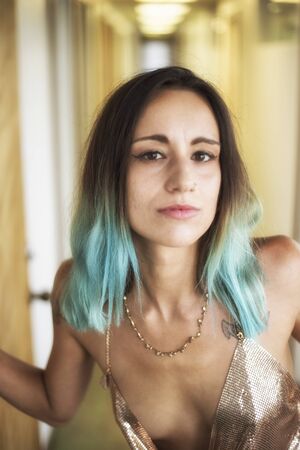 Photo of a very attractive woman with beautiful brown eyes. She is looking right at the camera and she is wearing a gold, metallic sleeveless top.の写真素材