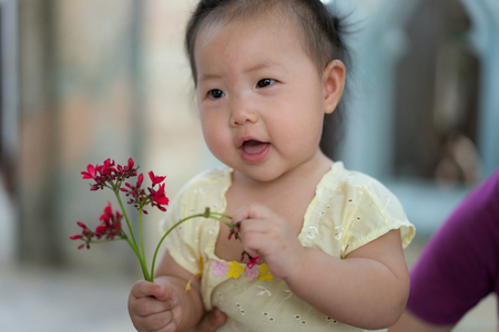Happy Asian baby girl with Thai traditional dress, Holding flowers in hand.の写真素材