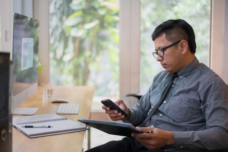 Businessman working on smart phone in office, business concept.