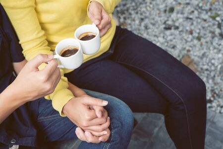 Couples holding hands and drinking coffee in the garden at coffee shop.