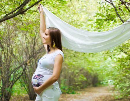 Beautiful pregnant woman outside in the parkの写真素材